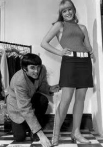 British footballer George Best measures the hemline of a Sixties model.
